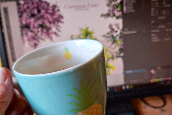 Teetasse in Türkis vor einem Bildschirm (unscharf im Hintergrund)